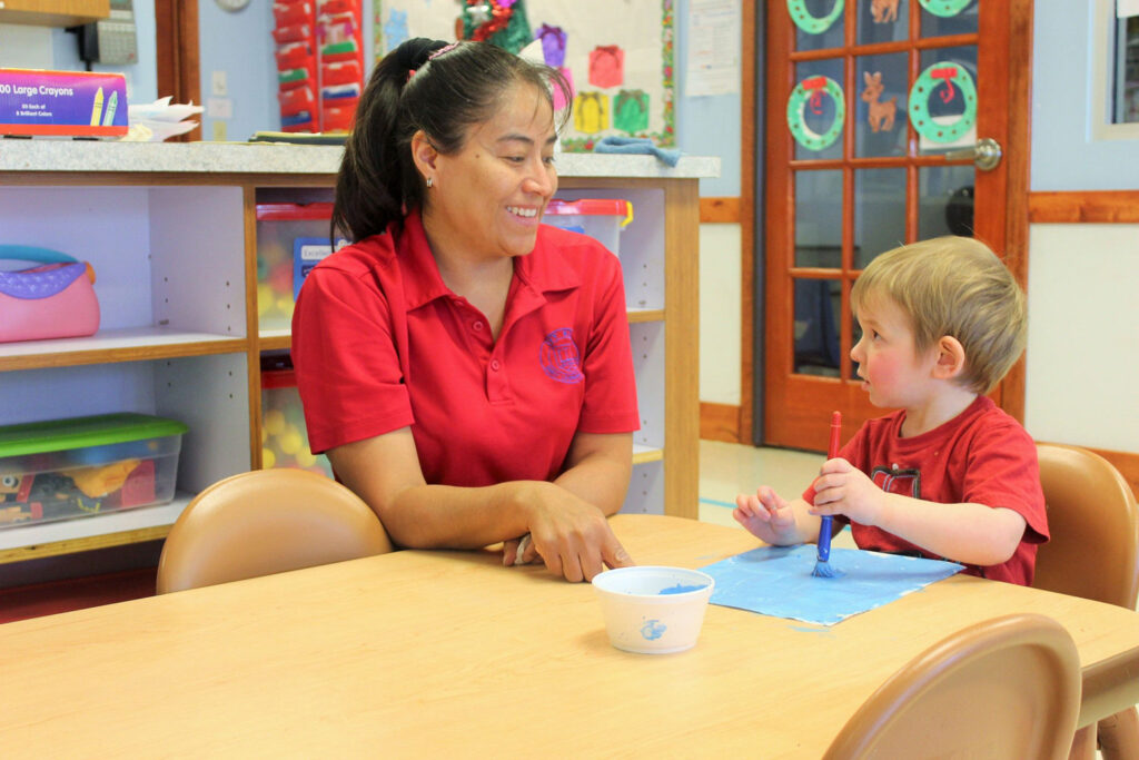 teaching a kid how to do art in a childcare center