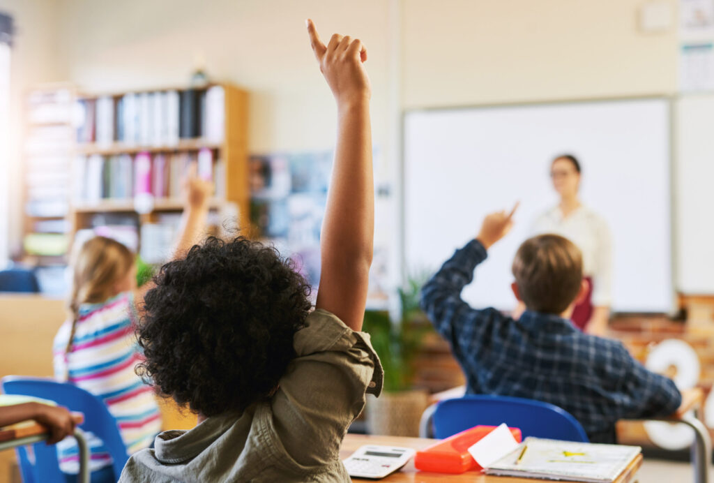 kids raising their hands inside the classroom