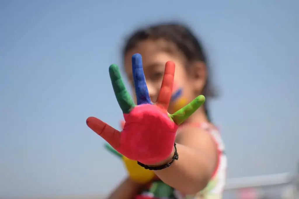 young girl raising her her painted to the camera