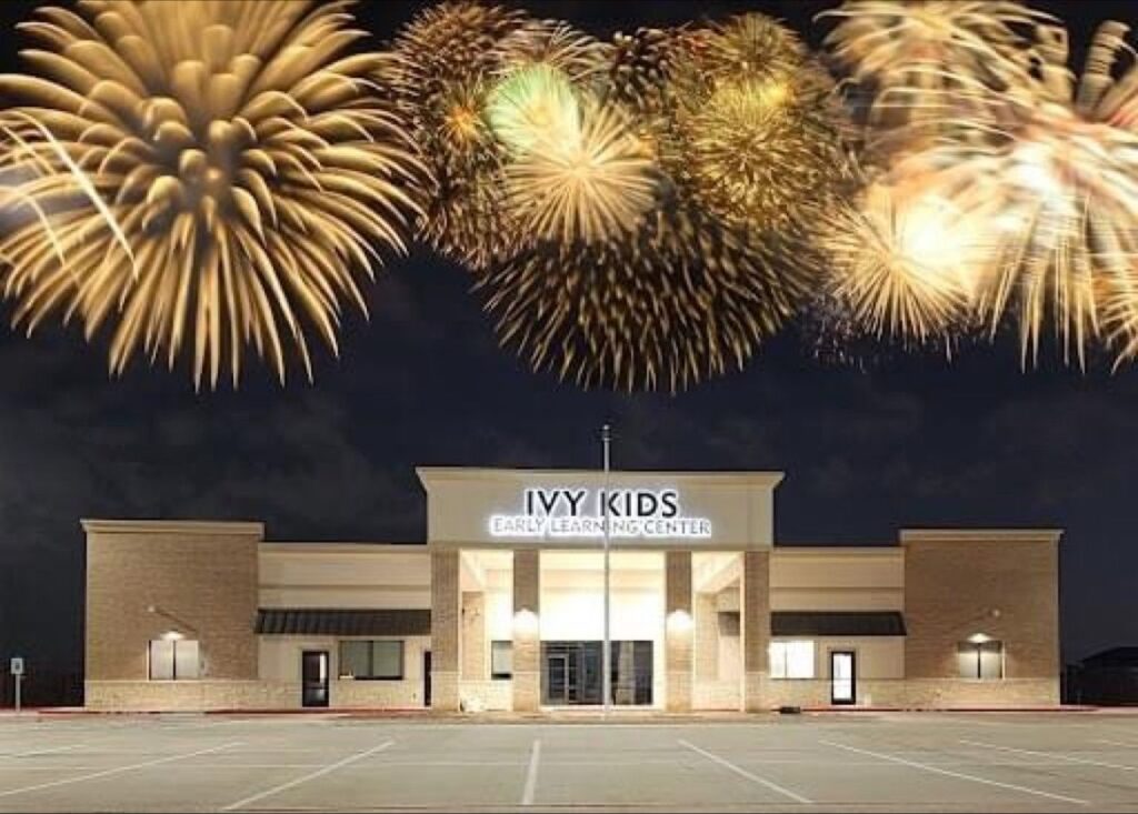 A building labeled "Ivy Kids Early Learning Center" with bright fireworks illuminating the night sky above it.